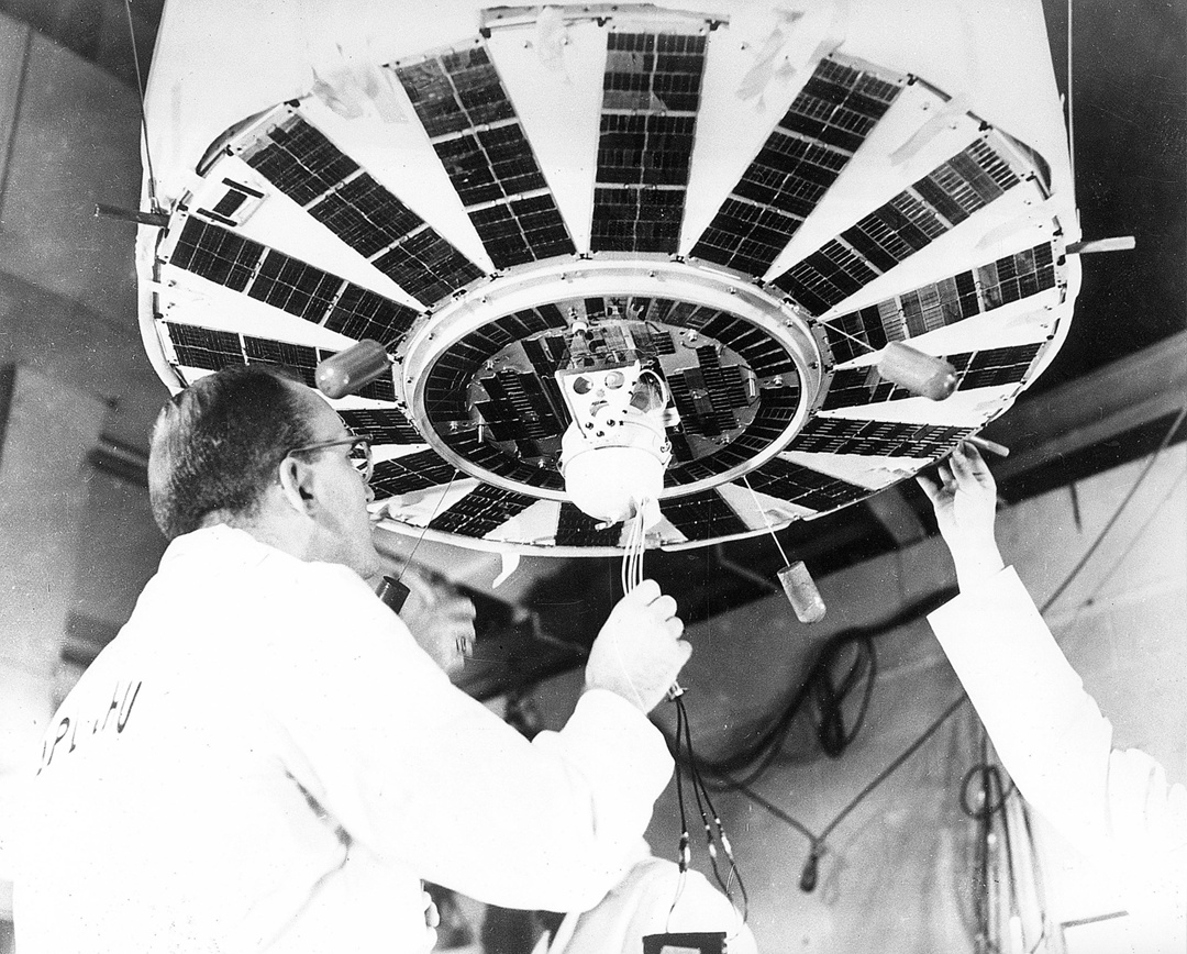 Johns Hopkins University staff carefully mounting a SNAP RTG onto the base of a TRANSIT navigation satellite (preparing for vibration testing). Photo from the US Department of Energy archives